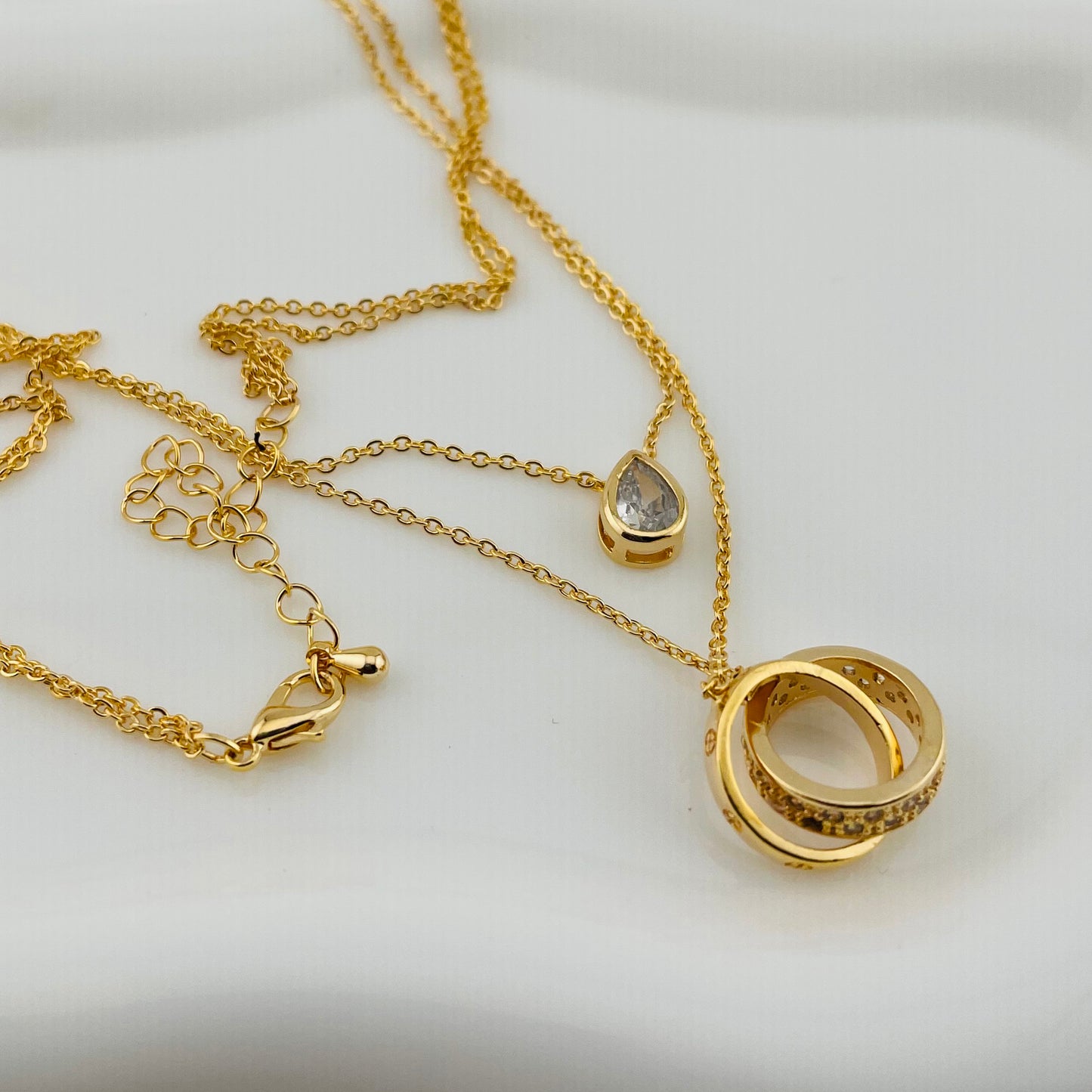 Dual Layered Necklace with Teardrop Stone & Interlocking Rings Pendant – Adjustable Chain | Imitation Gold